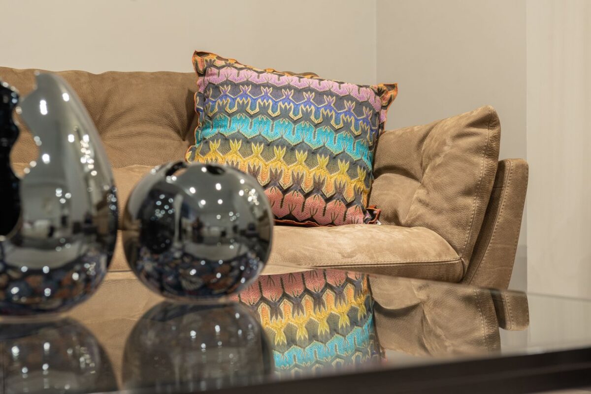 Services Modern living room interior with comfortable sofa and colorful cushion near table with glass tabletop and shiny decorations